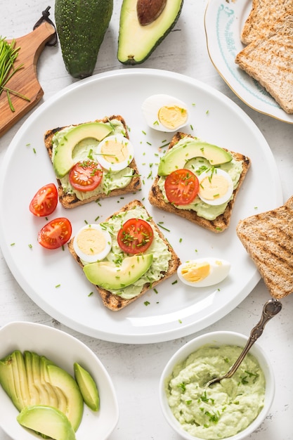 Desayuno saludable a base de tostadas con aguacate, guacamole, huevo, tomate y cebollino.