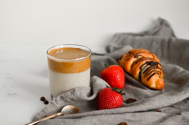 Desayuno saludable: café frío Dalgona, croissant y fresas en blanco