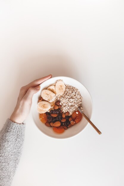 Desayuno saludable con carbohidratos. Avena con frutos secos en un plato blanco. Vista desde arriba