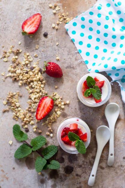 Desayuno saludable casero con granola horneada casera, fresa fresca y yogur en piedra