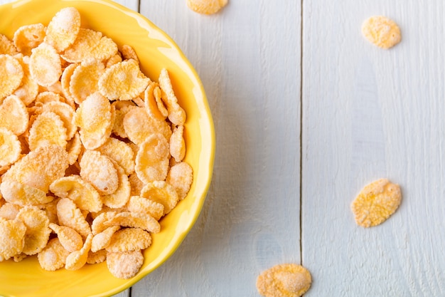 Desayuno saludable con copos de cereales sobre fondo blanco. Tono amarillo Vista superior.