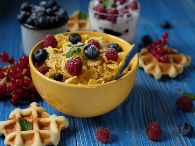 Desayuno saludable con copos de maíz, bayas, gofres y leche.