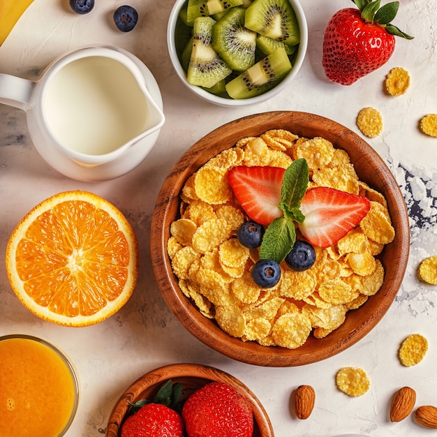 Desayuno saludable con copos de maíz y frutas frescas.