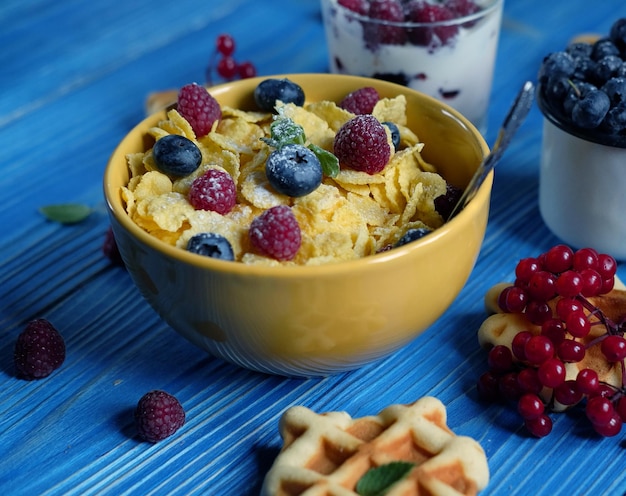 Foto desayuno saludable corn flakes con frambuesas y arándanos granola con yogur y barquillos de bayas y leche un gran comienzo del día vista superior