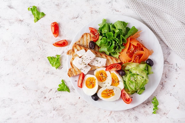 Foto desayuno saludable ensalada con huevos de queso feta pepino y zanahoria comida sana y equilibrada vista superior endecha plana