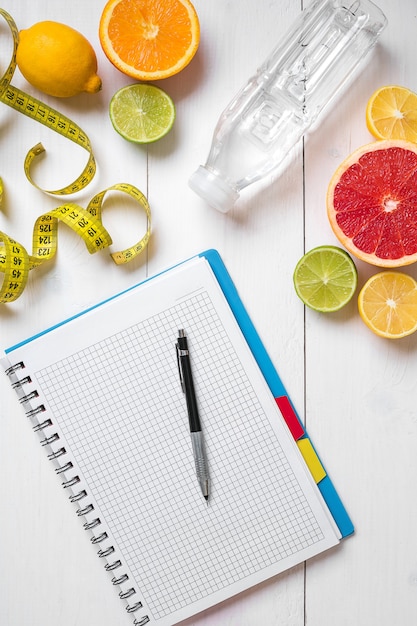 Desayuno saludable con frutas frescas y botella de agua con cuaderno sobre mesa de madera rústica