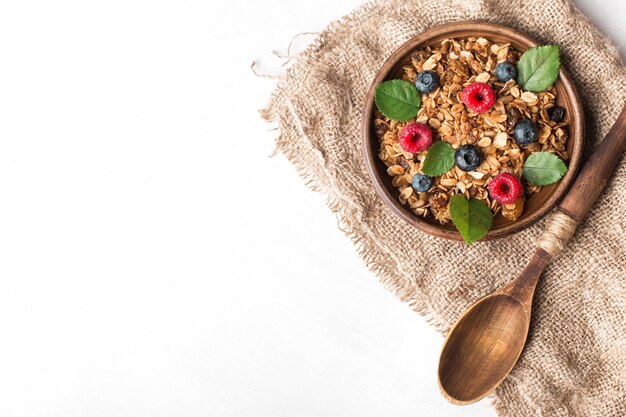 Desayuno saludable con granola y bayas sobre fondo blanco.