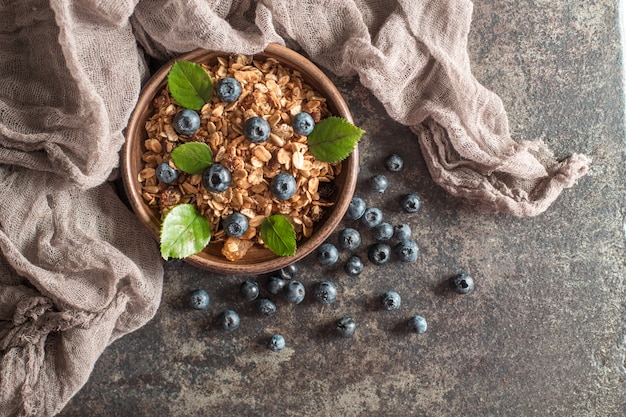 Desayuno saludable con granola y bayas sobre fondo oscuro.