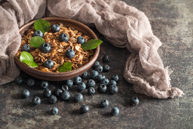 Desayuno saludable con granola y bayas sobre fondo oscuro