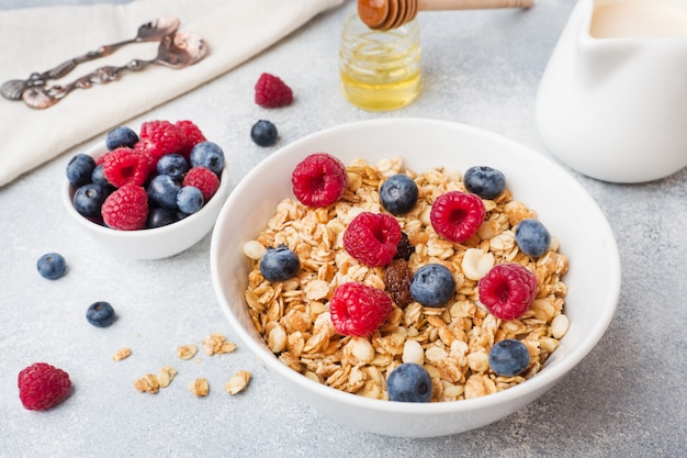 Desayuno saludable. Granola fresca, muesli con yogur y bayas en la mesa gris. Copia espacio