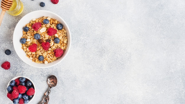 Desayuno saludable. Granola fresca, muesli con yogur y bayas en la mesa gris. Copia espacio