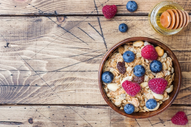 Desayuno saludable. Granola fresca, muesli con yogur y bayas sobre superficie de madera