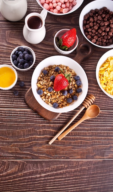 Foto desayuno saludable. granola, muesli con bayas frescas y otros copos y bolas de maíz en el fondo. vista superior.