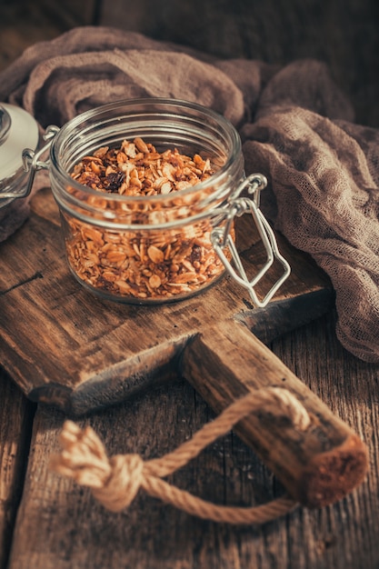 Desayuno saludable con granola en recipiente de vidrio sobre fondo oscuro