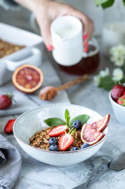 Foto desayuno saludable con granola, yogurt, frutas, bayas en un plato blanco en plato blanco.