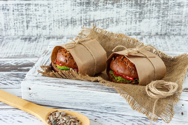 Desayuno saludable - hamburguesa con salmón ahumado, ensalada de hojas y aguacate servido en un papel artesanal sobre fondo de madera, horizontal.