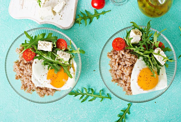 Desayuno saludable con huevo, queso feta, rúcula, tomate y gachas de alforfón