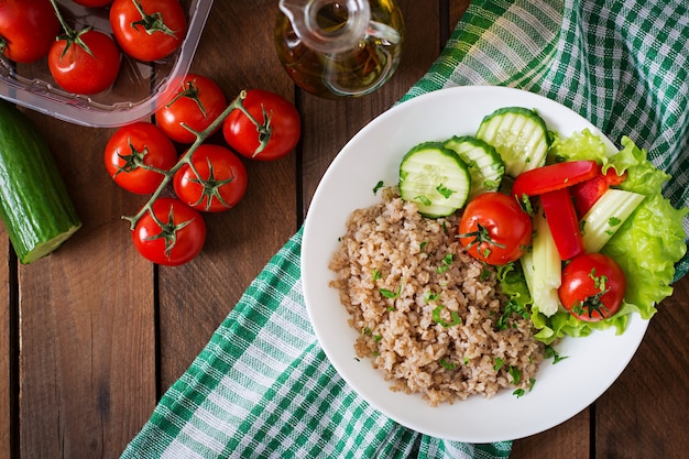 Desayuno saludable con huevo, queso feta, rúcula, tomate y gachas de trigo sarraceno sobre fondo claro. Nutrición apropiada. Menú dietético Endecha plana. Vista superior