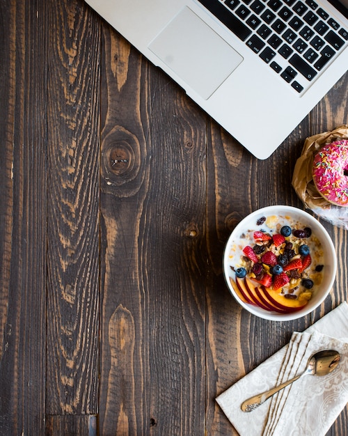 Desayuno saludable con leche, muesli y fruta, sobre un fondo de madera.