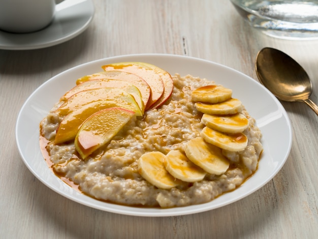 Desayuno saludable en la mañana: avena con frutas y miel, rodajas de manzanas y panza.