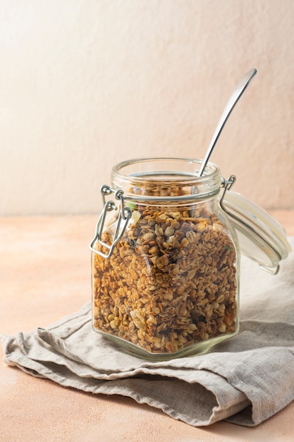 Desayuno saludable, muesli, en un frasco de vidrio alto sobre un fondo rosa