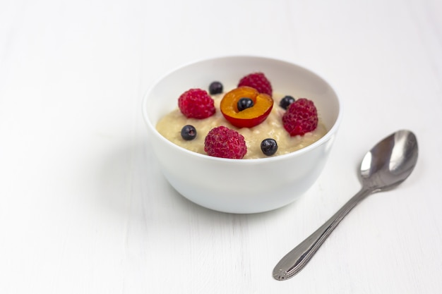 Desayuno saludable para niños. Tazón de comida para bebés en madera blanca