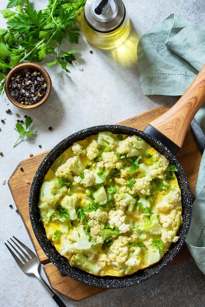 Desayuno saludable o almuerzo dietético Tortilla de huevo con coliflor en una sartén de hierro fundido