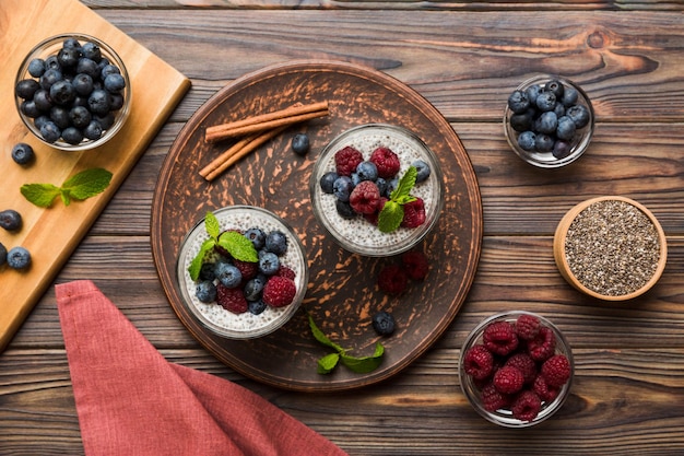 Desayuno saludable o mañana con semillas de chía, pudín de vainilla, frambuesa y bayas de arándanos en el fondo de la mesa, comida vegetariana, dieta y concepto de salud, Pudín de chía con frambuesa y arándanos