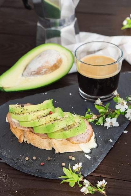 Desayuno saludable Pan de grano tostado con jamón de aguacate fresco en rodajas y taza de café