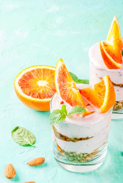 Desayuno saludable, Parfait de naranja sanguina con granola. yogurt, almendra y menta, azul claro, copyspace