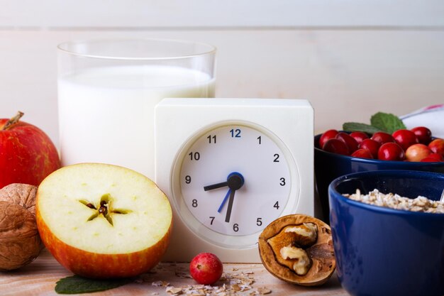 Desayuno saludable reloj leche avena arándanos nueces manzanas en una mesa de madera