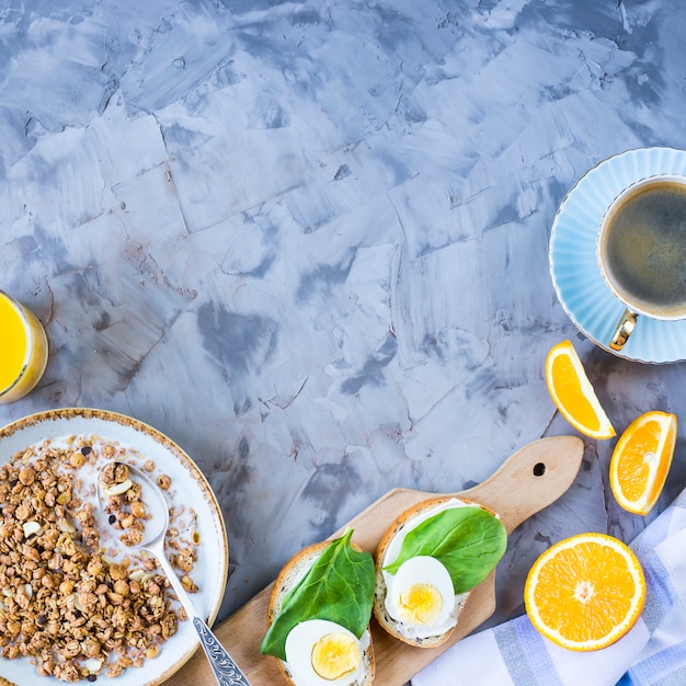 Desayuno saludable y saludable: muesli, sándwich con huevo, café, naranja y jugo