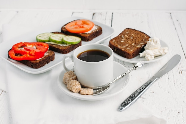 Desayuno saludable con sándwiches vegetarianos y café.