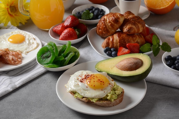 Desayuno saludable Tostadas con aguacate y huevo tocino y huevos frutas frescas y secas jugo fresco