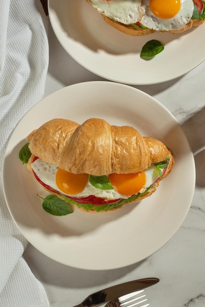 Desayuno saludable y útil Croissant con aguacate y huevos en una mesa gris