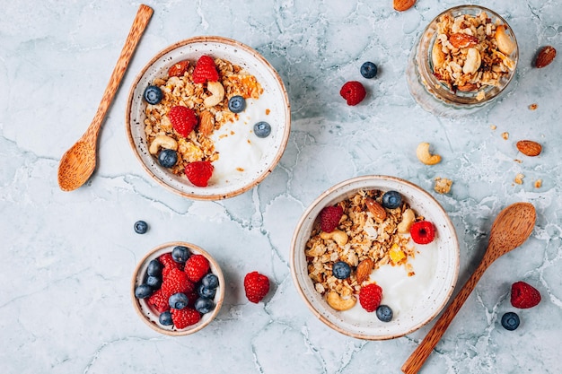 Desayuno saludable con yogur y granola horneada con bayas en dos tazones pequeños