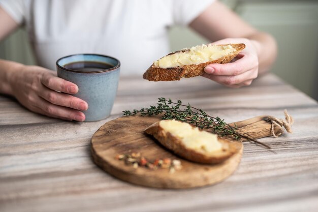 desayuno de un sándwich con mantequilla en una tabla de madera y una taza de café
