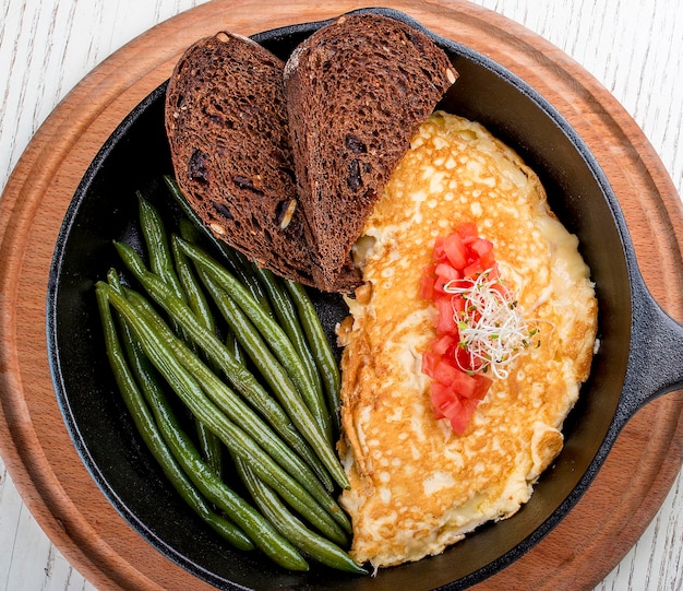 Desayuno en una sartén sobre un fondo blanco Huevos revueltos con espárragos y tostadas