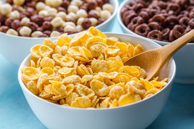 Desayuno seco, cereales. Cuchara y tazón con copos de maíz amarillo esmerilado