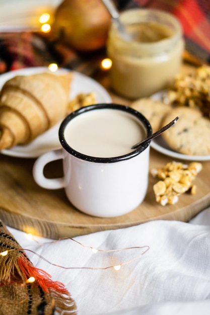 Desayuno sencillo en casa de campo en la cama, café con leche y repostería casera sobre una manta a cuadros