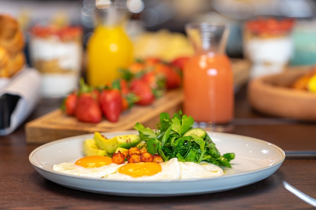 Desayuno servido con huevos, jugo de naranja, croissants, fresas, dieta equilibrada.