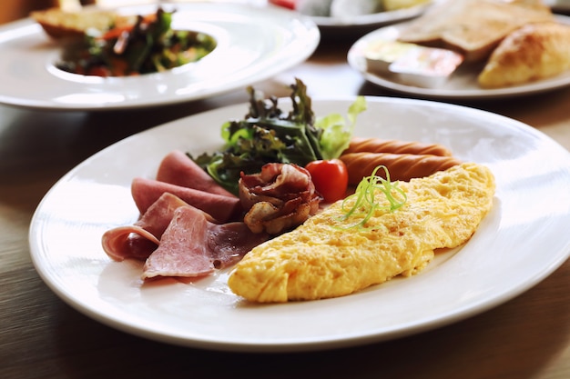 Desayuno set tortilla con salchicha tocino y ensalada en madera