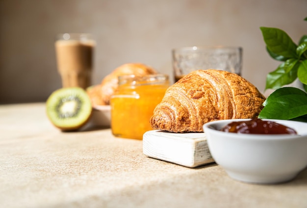 Desayuno con una taza de café croissant crujiente fresco mermelada de kiwi y jugo Desayuno de verano