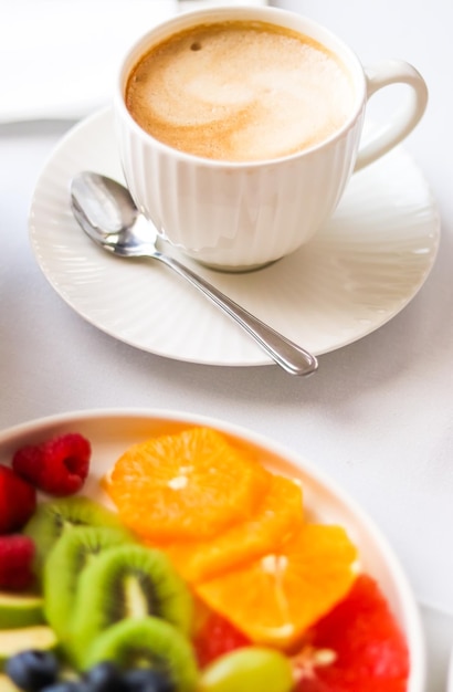 Desayuno y taza de café de lujo con plato de leche y fruta en la mesa servida para hostelería y gastronomía