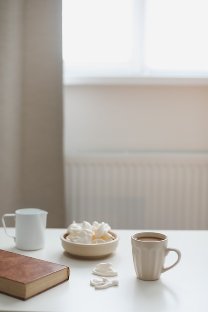 Desayuno con una taza de café sobre una mesa blanca