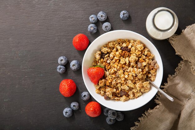 Desayuno con tazón de granola bayas frescas y botella de leche vista superior