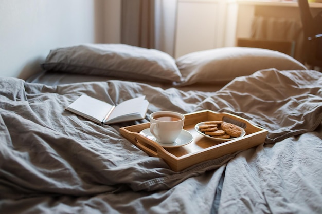 Desayuno de té y galletas con un Bloc de notas y un bolígrafo en una cama gris por la mañana