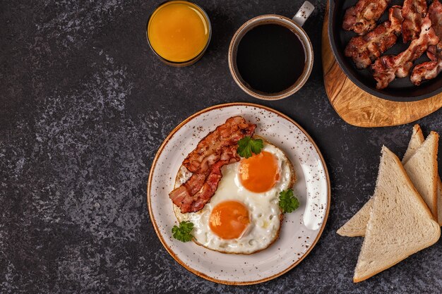 Desayuno con tocino, huevo frito, café y jugo de naranja.