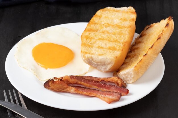 Desayuno con tocino, huevo y pan.