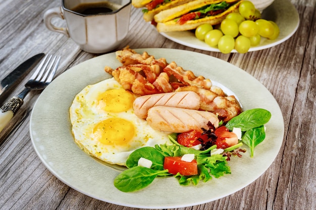 Desayuno tradicional inglés con tocino, huevos, salchichas, ensalada y tostadas de queso a la parrilla.